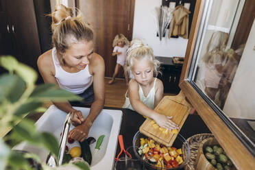 Mutter und Tochter bereiten gemeinsam einen Salat in der Küche zu - SIF00595