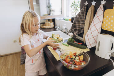 Girl collecting organic waste from vegetables in kitchen - SIF00602