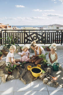 Mutter und Töchter pflanzen gemeinsam Blumen auf der Dachterrasse - SIF00603