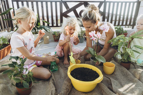Mutter und Töchter pflanzen gemeinsam Blumen auf der Dachterrasse - SIF00604