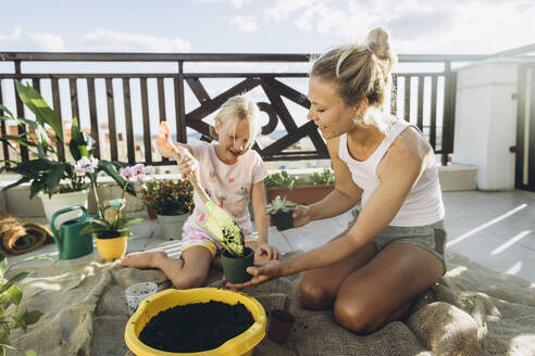Mother and daughter planting on roof terrace together - SIF00611