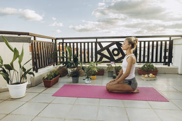 Woman meditating on roof terrace - SIF00618