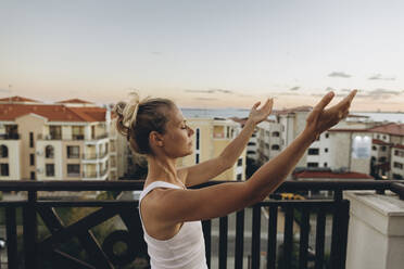 Gelassene Frau genießt den Sonnenuntergang auf der Dachterrasse - SIF00648