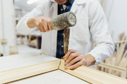 Hands of craftsman using work tool to make frame in workshop - MEUF08817