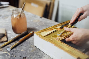 Craftsman with hand tool working on frame in workshop - MEUF08835