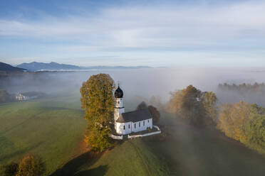 Germany, Bavaria, Bad Heilbrunn, Aerial view of Church of Visitation of Virgin Mary at foggy autumn dawn - LBF03669