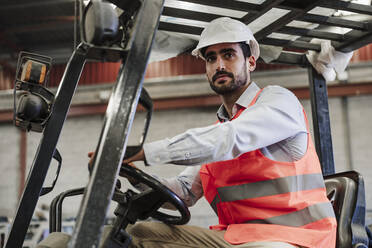 Engineer wearing protective workwear driving forklift in industry - EBBF07379