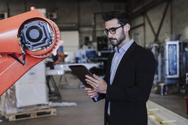 Ingenieur mit Tablet-PC an einem Roboterarm in der Industrie - EBBF07419