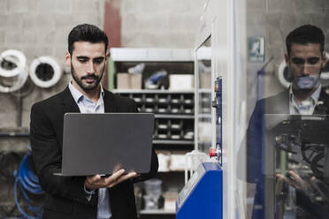 Ingenieur mit Laptop an einer Maschine in der Industrie - EBBF07448