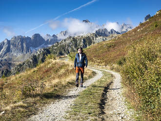 Älterer Mann, der an einem sonnigen Tag im Vanoise-Nationalpark, Frankreich, vor den Bergen spazieren geht - LAF02782