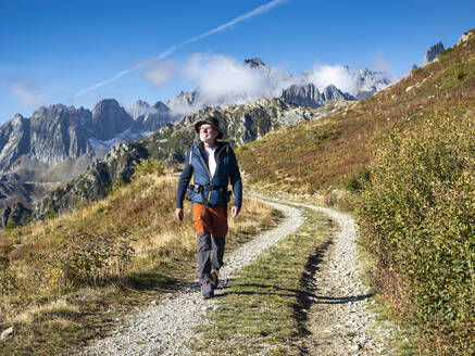 Aktiver älterer Mann, der an einem sonnigen Tag im Vanoise-Nationalpark, Frankreich, vor den Bergen spazieren geht - LAF02783