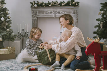 Mutter verpackt Weihnachtsgeschenk mit Kindern zu Hause - NDEF00246