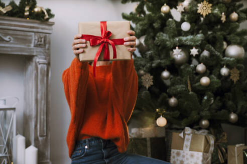 Woman holding Christmas present at home - NDEF00258