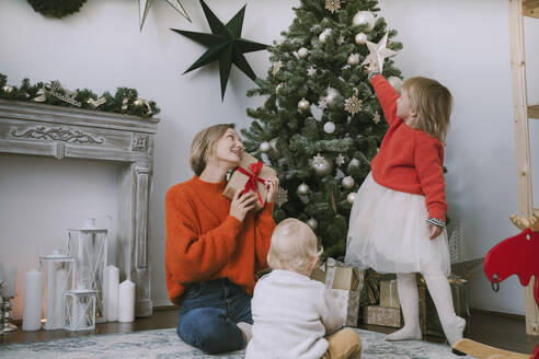 Mutter und Kinder sitzen zu Hause am Weihnachtsbaum - NDEF00259