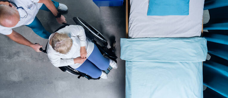 Top view of doctor pushing patient in wheechair in hospital. Copy space. - HPIF03092