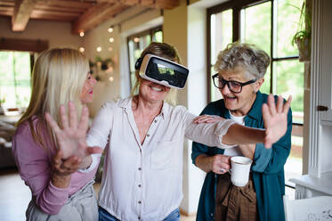 Happy senior women friends having fun with Virtual Reality Glasses imndoors at home. - HPIF03107