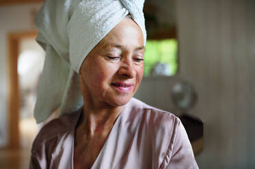 A happy senior women in bathrobe indoors at home, selfcare concept. - HPIF03115