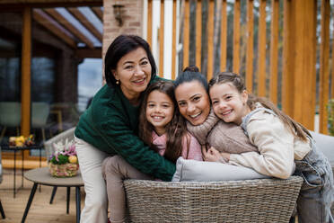 Two happy sisters with a mother and grandmother embracing and looking at camera outdoors in patio in autumn. - HPIF03169