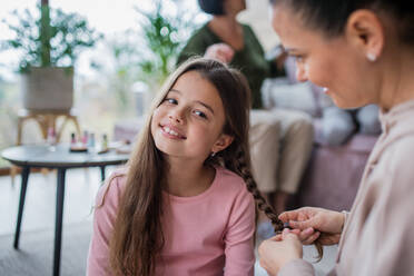 Eine Mutter macht ihrer kleinen Tochter zu Hause einen Zopf. - HPIF03191