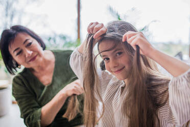 A grandmother helping her little granddaughter with making a hairstyle. - HPIF03192