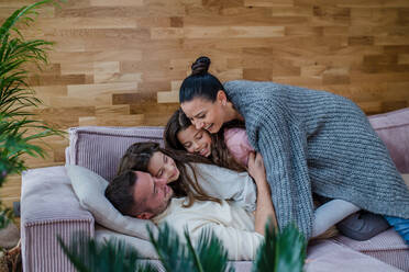 Two happy sisters having fun with a father nad mother, lying on sofa at home. - HPIF03206