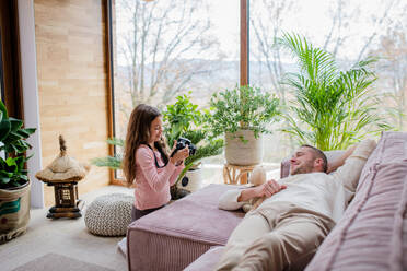 Ein kleines Mädchen fotografiert mit der Kamera ihren Vater, der zu Hause auf dem Sofa liegt. - HPIF03208