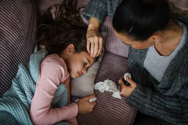 A high angle view of mother taking care of her sick daughter at home. - HPIF03222