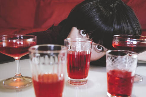Woman resting head by glasses on table in foreground - SVCF00220