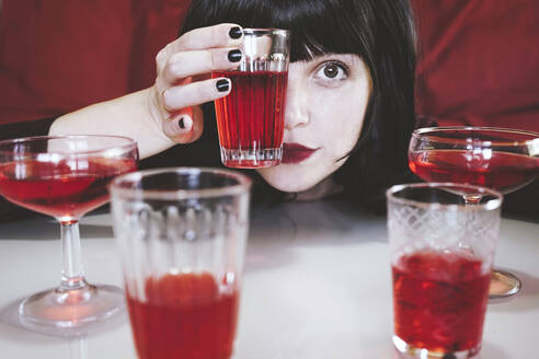 Frau bedeckt ihr Auge mit einem Glas eines roten alkoholischen Getränks - SVCF00221