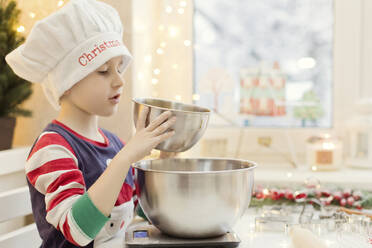 Junge mit Kochmütze bei der Zubereitung von Lebkuchen in der Küche - ONAF00294