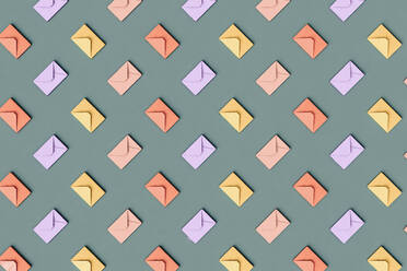 Three dimensional pattern of rows of pastel colored envelopes flat laid against green background - GCAF00235