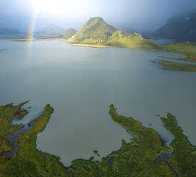 From above breathtaking drone view of green mountains and calm lake located in volcanic terrain against cloudy blue sky in Iceland - ADSF41599