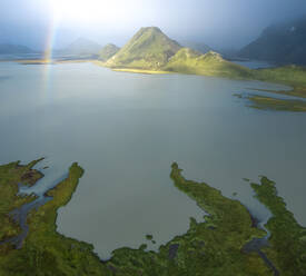 Von oben atemberaubende Drohne Blick auf grüne Berge und ruhigen See in vulkanischen Gelände gegen bewölkten blauen Himmel in Island gelegen - ADSF41599