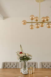 Zeitgenössisches Esszimmer mit Holztisch und Stühlen mit Blumen und moderner Lampe - ADSF41612
