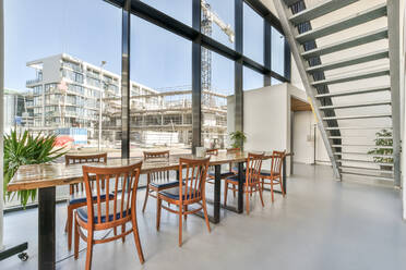 Holztisch in einem stilvollen, hellen, geräumigen Esszimmer mit Fenstern in einer modernen Wohnung mit Treppe - ADSF41638