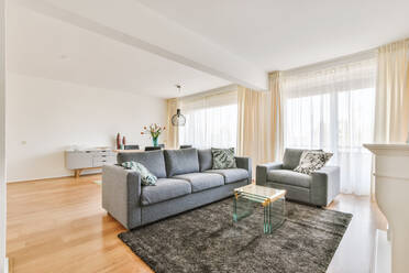 Bequemes Sofa auf Teppich mit Tisch an der Wand mit Kamin im stilvollen Wohnzimmer - ADSF41651