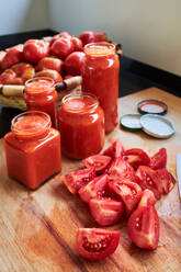 From above ripe red tomatoes and jars of sauce placed on table in kitchen - ADSF41689