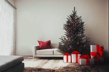 Vorderansicht eines Innenraums mit einem Weihnachtsbaum neben einigen Geschenken und einem Sofa - ADSF41763