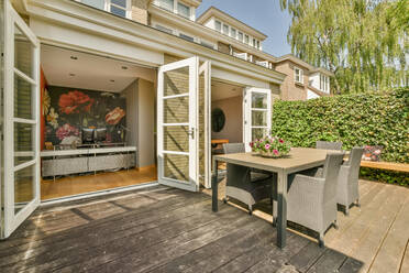 Backyard of a house next to other houses lined up with table and chairs - ADSF41908