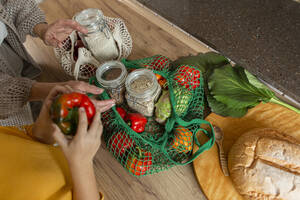 Grandmother and granddaughter unpacking fresh groceries in kitchen - LLUF00965