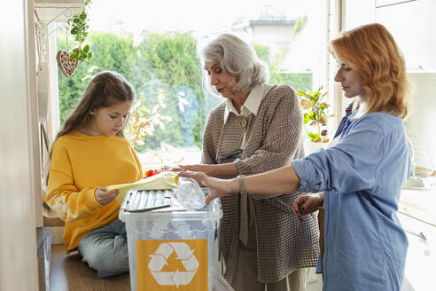 Großmutter, Mutter und Tochter sortieren Recyclingabfälle in der Küche - LLUF00998