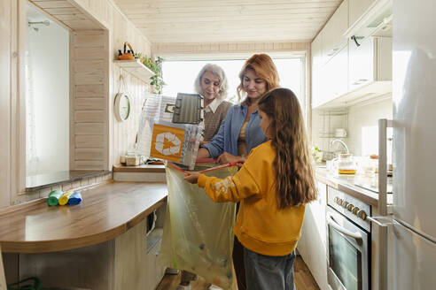 Großmutter, Mutter und Tochter sortieren Recyclingabfälle in der Küche - LLUF00999