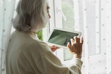 Ältere Frau stellt die Temperatur am Smart Home-Gerät ein - LLUF01004