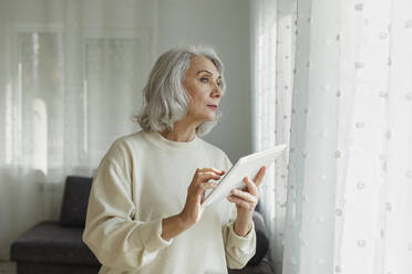 Ältere Frau hält digitales Tablet zu Hause - LLUF01006