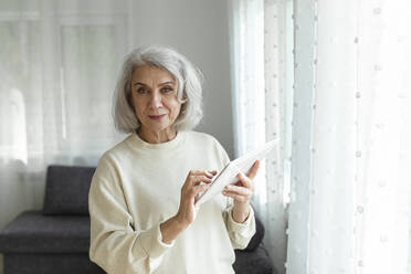 Ältere Frau hält digitales Tablet zu Hause - LLUF01007
