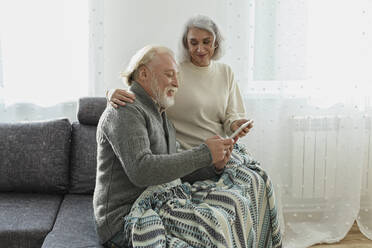 Älteres Paar sitzt mit digitalem Tablet auf der Couch - LLUF01009