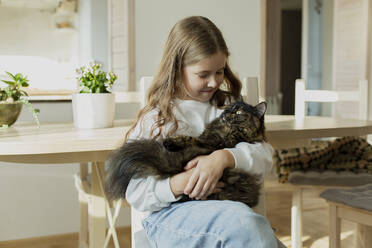 Mädchen hält eine Katze zu Hause - LLUF01014