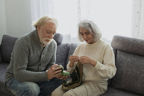 Älteres Paar sitzt auf der Couch und strickt - LLUF01019