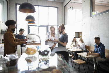 Barista am Tresen, der lächelnden Kunden Kaffee serviert - NURF00003