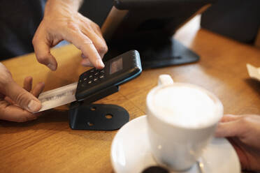 Hände eines Kassierers, der eine Kartenmaschine in einem Café benutzt - NURF00006